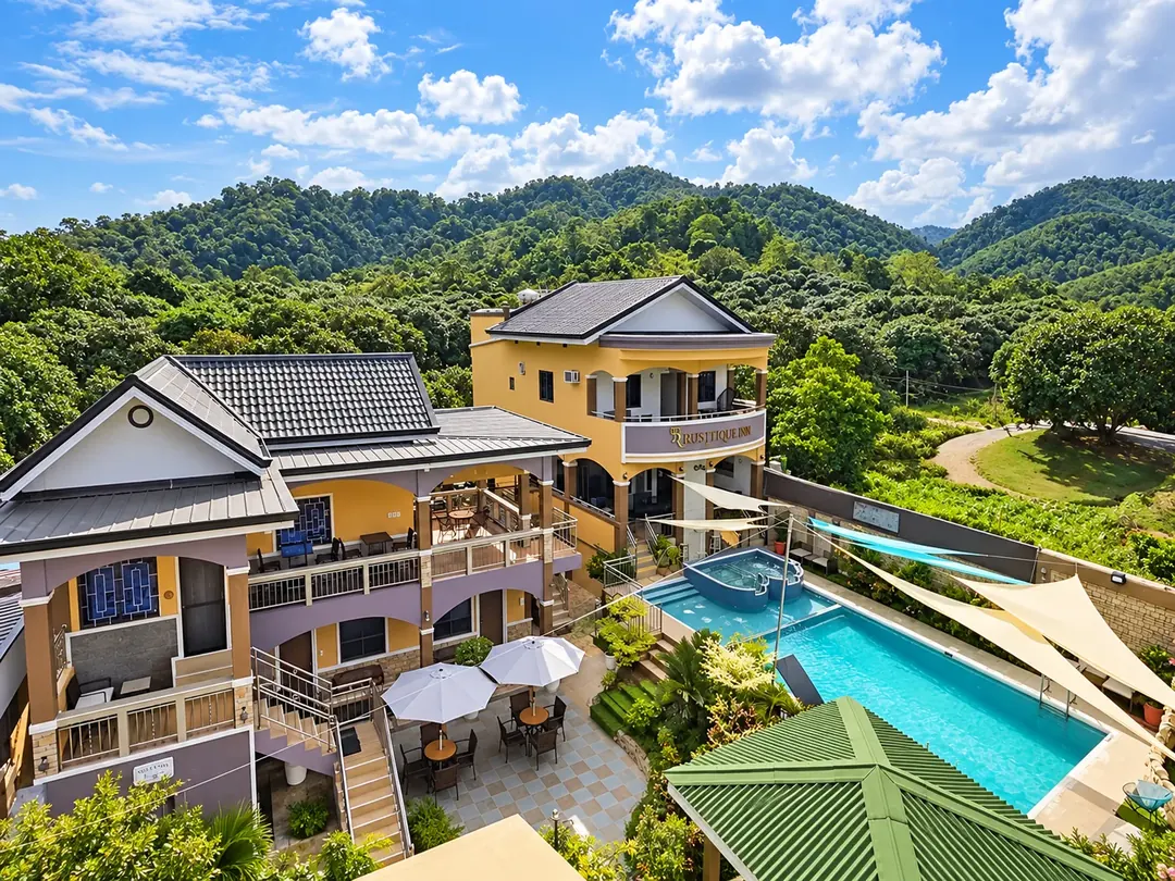 Aerial view of the resort with its swimming pool and the green hills behind