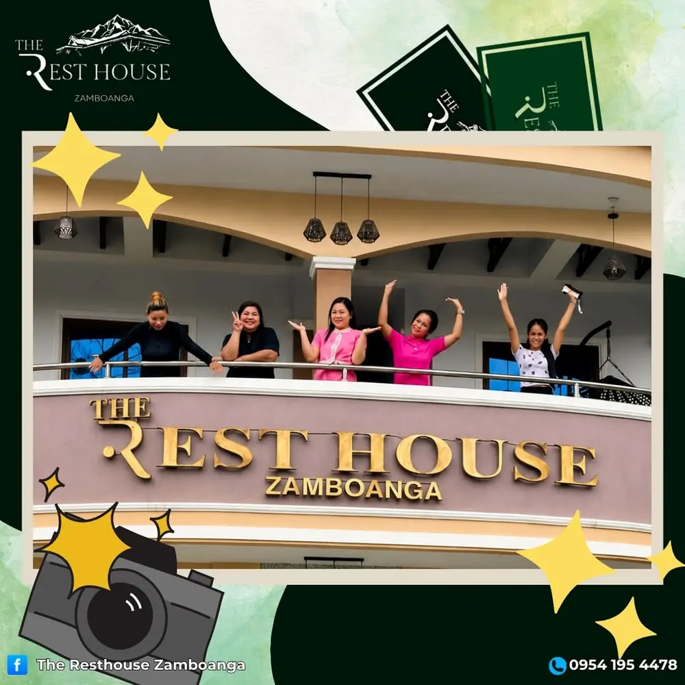 Five friends waving from the resort balcony above the gold resort signage